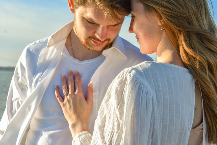 Photos of a newly engaged couple on a beach in winter at sunset wearing all white