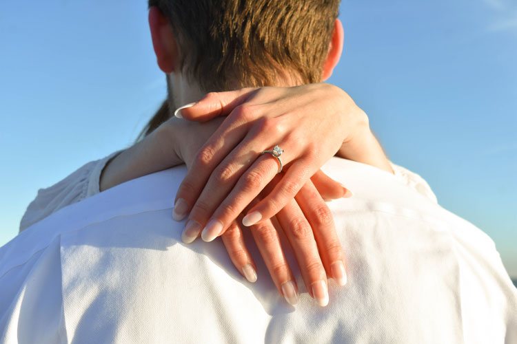 Photos of a newly engaged couple on a beach in winter at sunset wearing all white