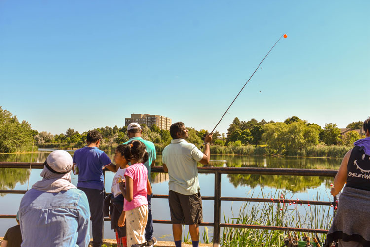 Families fishing at Lake Aquitaine on Family Fishing Day - one man specific has his rod in the air ready to cast