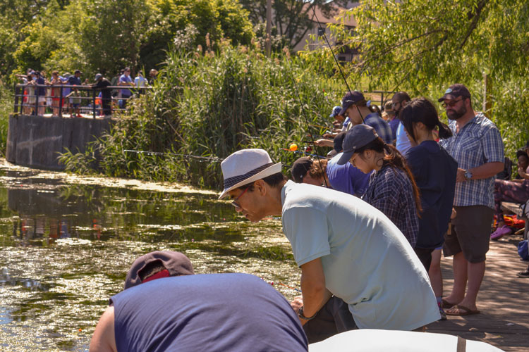Families fishing off the dock at Lake Aquitaine on Family Fishing Day