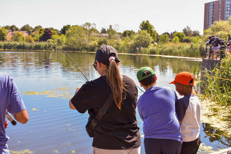 Families fishing off the dock at Lake Aquitaine on Family Fishing Day