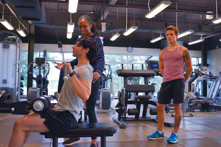 participant doing a chest pull down alongside a trainer at a group fitness class at the fitness centre at the Paramount Fine Foods Centre
